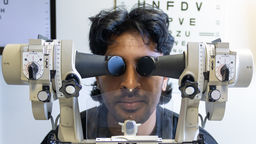 A man looks through orthoptics equipment