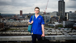 Elliot wearing blue scrubs, Sheffield skyline in background