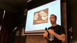  Dr Hazem Toutounji standing in front of a projector and talking into a microphone