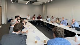 participants of the symposium sit in a workroom in the round for discussion