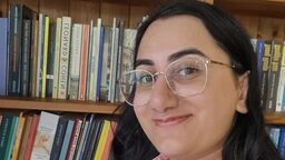student stood in front of book shelf.