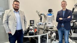 Nick Thompson, CEO of BOW, stood next to Daniel Camilleri, CTO and Founder of BOW with some robots in the background