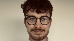 Person with glasses smiling to the camera 
