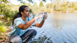 Female scientist taking samples by water 